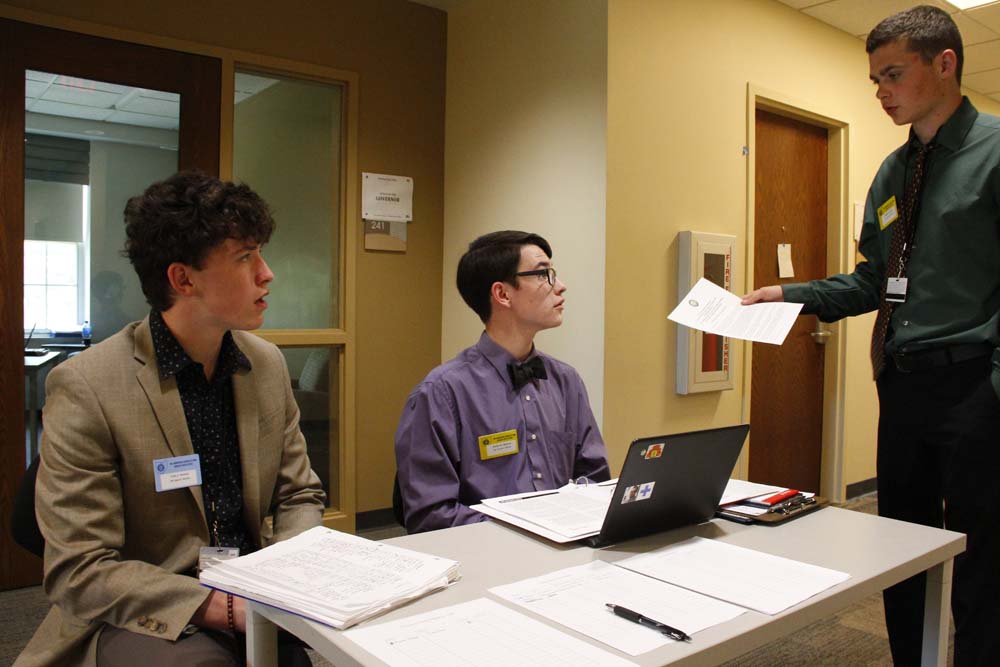 Delegates in a discussion surrounded by paperwork